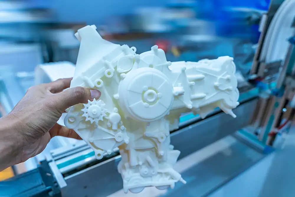 It shows a 3D printed, complex mechanical component being held in the hand.