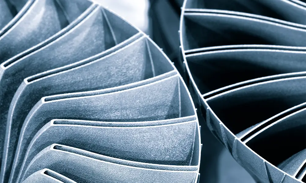 Close-up of the turbine blades of an aircraft engine, which are arranged symmetrically and precisely. The metallic structures show detailed aerodynamic shapes.