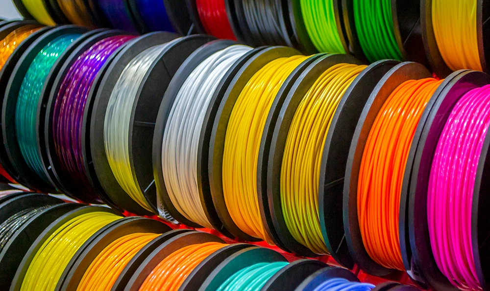 Several spools of colorful 3D printing filament or plastic wire are arranged next to each other.