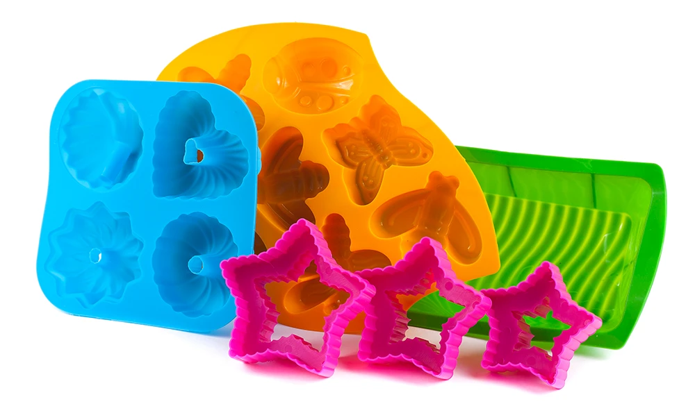 Various colorful silicone molds in blue, orange and green as well as pink star-shaped cookie cutters. The molds are intended for baking or crafting and show different patterns such as hearts, butterflies and flowers.