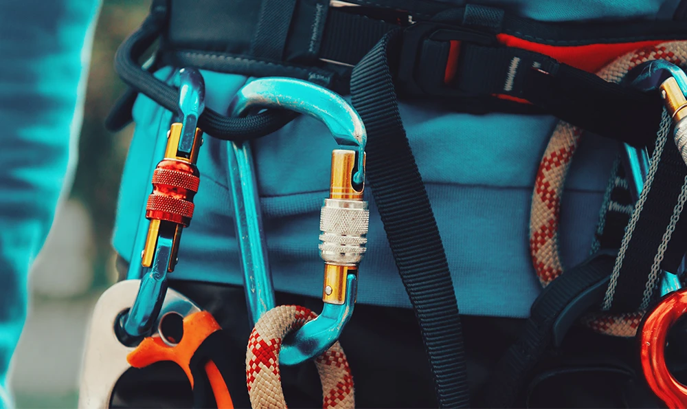 A climbing harness with several carabiners, ropes and safety equipment is worn by one person.