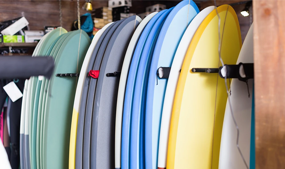 Several colorful surfboards stand upright in a surf shop or warehouse.